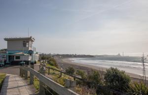 een strand met een gebouw en de oceaan bij Spacious In Strandon Great Value For A Family in New Plymouth