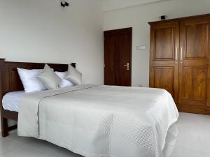 a bedroom with a white bed and a wooden cabinet at Luxury 3 bed flat in Colombo 7 in Colombo