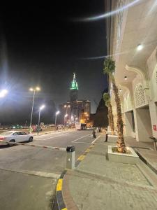 فندق أبراج نوازي  في مكة المكرمة: شارع المدينة في الليل مع مبنى ذو اضاءة خضراء