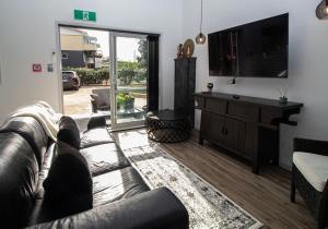 a living room with a leather couch and a television at City Living Apartment Three in New Plymouth