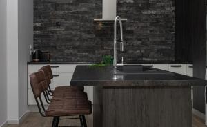 a kitchen with a sink and a counter with a chair at City Living Apartment Three in New Plymouth
