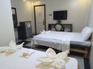 a hotel room with two beds and a tv at Bayside Exceel Hotel in Puerto Galera