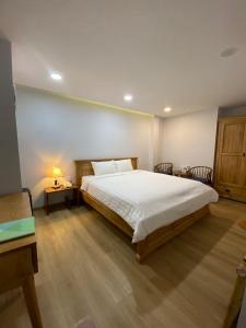 1 dormitorio con 1 cama, mesa y sillas en Khách Sạn Măng Đen Xanh en Kon Plong