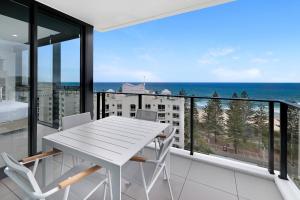 a white table and chairs on a balcony with the ocean at Sandbar Burleigh in Gold Coast
