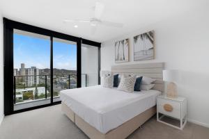 a bedroom with a white bed and large windows at Sandbar Burleigh - Official in Gold Coast