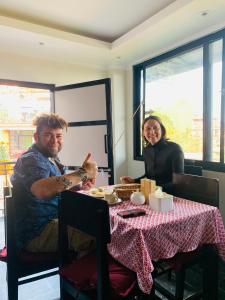 a man and a woman sitting at a table at Bandipur Samira Homestay - Experience the Best for Less in Bandīpur