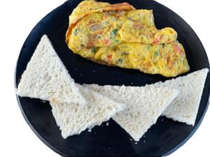 a black plate with an omelet and two pieces of bread at VITS Daman Devka Beach in Daman