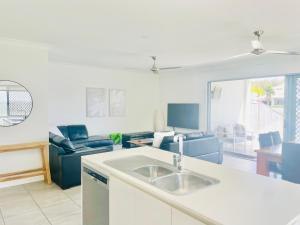 uma cozinha com um lavatório e uma sala de estar em Blue Lagoon Villa B em Cairns