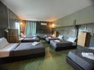 a hotel room with four beds and a couch at Baanrimfai Homestay in Ban Thung Sang