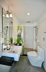 a white bathroom with a toilet and a sink at PapaCrab Boutique Guesthouse in Kamala Beach