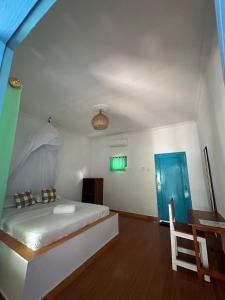 a bedroom with a bed and a desk and green doors at Melbao Homestay in Gili Air