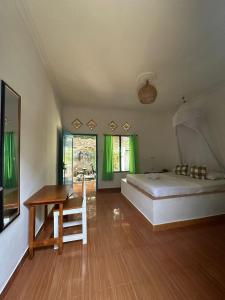 a bedroom with a bed and a desk and green curtains at Melbao Homestay in Gili Air