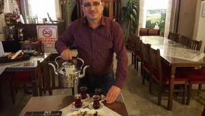 a man holding a tea kettle on a table at Demirkapi Konak Hotel in Safranbolu