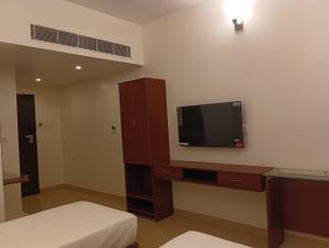 a bedroom with a tv and a bed and a desk at Le MIAMI RESORT in Pondicherry