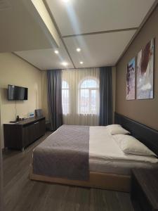 1 dormitorio con 1 cama grande y TV en Bien hotel en Ereván