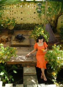 una mujer con un vestido naranja de pie en un banco en Trầm Homestay, en Thôn An Hòa
