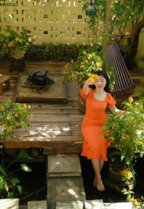 una donna con un vestito arancione in piedi in un giardino di Trầm Homestay a Thôn An Hòa