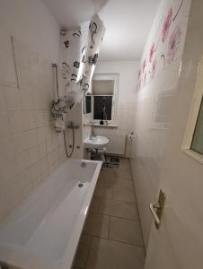 Baño blanco con bañera y lavamanos en NB Vogelviertel zwei Zimmer Wohnung en Nuevo Brandeburgo