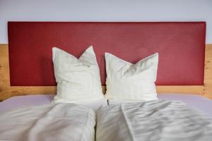 two pillows on a bed with a red headboard at Berggasthof Hochzeigerhaus in Jerzens