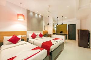 a bedroom with two beds with red pillows at Angson Apartment in Chennai
