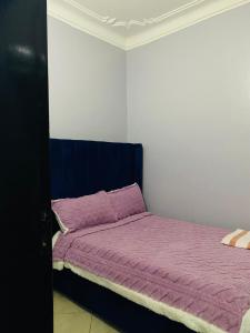 sypialnia z łóżkiem z fioletowym kocem w obiekcie Adea Apartments Munyonyo w mieście Kampala