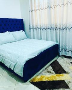 łóżko z niebieskim zagłówkiem w sypialni w obiekcie Adea Apartments Munyonyo w mieście Kampala