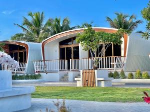 a white building with palm trees in the background at สต็อกโฮม เขาใหญ่ (StockHome Khao Yai) in Khanong Phra