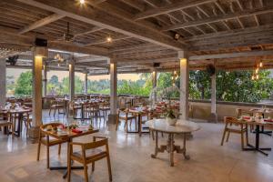 a dining room with tables and chairs and large windows at Wapa di Ume Ubud in Ubud