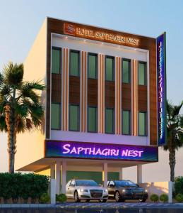 two cars parked in front of a saphir nest building at Hotel Sapthagiri Nest in Coimbatore