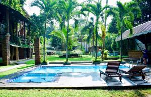 einen Pool mit 2 Stühlen und Palmen in der Unterkunft Airport Heritage Hotel in Katunayaka
