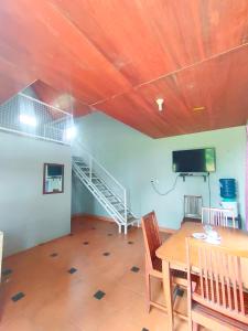 uma sala de jantar com uma mesa e uma televisão e uma escada em Degung Hillside em Bogor
