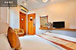 a bedroom with a bed and a tv on the wall at HANZ Happy Hotel in Ho Chi Minh City