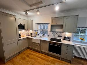una cocina con armarios blancos y electrodomésticos blancos en Wanton Wa's, en Nine Mile Burn