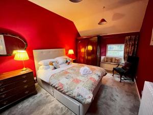 a bedroom with a red wall with a bed and a desk at Wanton Wa's in Nine Mile Burn