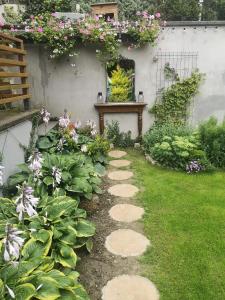 un giardino con un sentiero fiorito e una panchina di Domek przy lesie 2 a Danzica