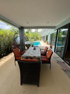 a patio with a table and chairs and a pool at Roland Villa in Koh Samui 