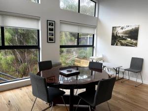 a dining room with a table and chairs and windows at Tree Top Vista Nornalup in Nornalup