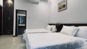 2 łóżka w pokoju hotelowym z białą pościelą w obiekcie Huy Hoàng Hotel w mieście Phan Thiet