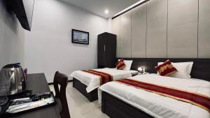 a hotel room with two beds and a television at Huy Hoàng Hotel Phan Thiet in Phan Thiet