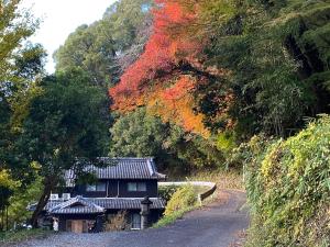 een huis aan de kant van een weg met bomen bij Kizuna Guesthouse 