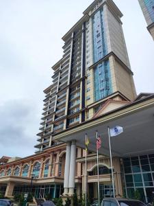 a large building with two flags in front of it at The Foreigner Staycation at Riverine Diamond Kuching in Kuching