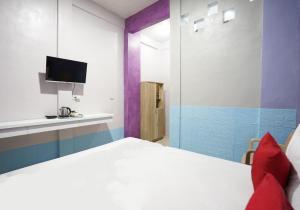 a bedroom with a white bed and a tv at FA Homestay Syariah at Babat Lamongan Mitra RedDoorz in Lamongan