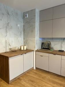 a kitchen with white cabinets and a marble wall at Nowoczesny apartament w centrum Starego Miasta, strzeżony parking in Zamość
