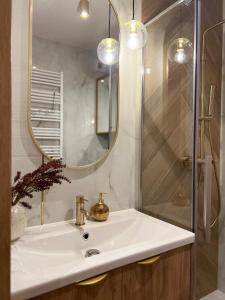 a bathroom with a sink and a shower with a mirror at Nowoczesny apartament w centrum Starego Miasta, strzeżony parking in Zamość +6 photos