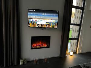 TV de pantalla plana colgada en una pared con chimenea en Enkhuizer Strand Chalet ZweiZeit Dritte Reihe Haus Nr 260, en Enkhuizen