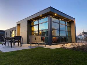 a glass house with a table and chairs on a patio at Enkhuizer Strand Chalet Möwennest Zweite Reihe Haus Nr 261 in Enkhuizen