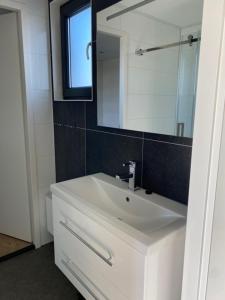 La salle de bains est pourvue d'un lavabo blanc et d'un miroir. dans l'établissement Enkhuizer Strand Chalet Möwennest Zweite Reihe Haus Nr 261, à Enkhuizen