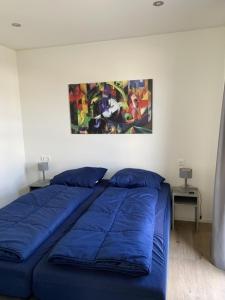a bedroom with a blue bed with a painting on the wall at Enkhuizer Strand Chalet Möwennest Zweite Reihe Haus Nr 261 in Enkhuizen