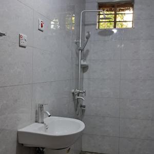 a white bathroom with a sink and a shower at JozaniBiospherevillage in Jozani