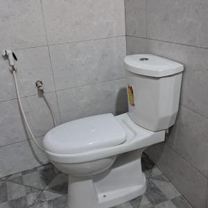 a white toilet in a bathroom with a hose at JozaniBiospherevillage in Jozani